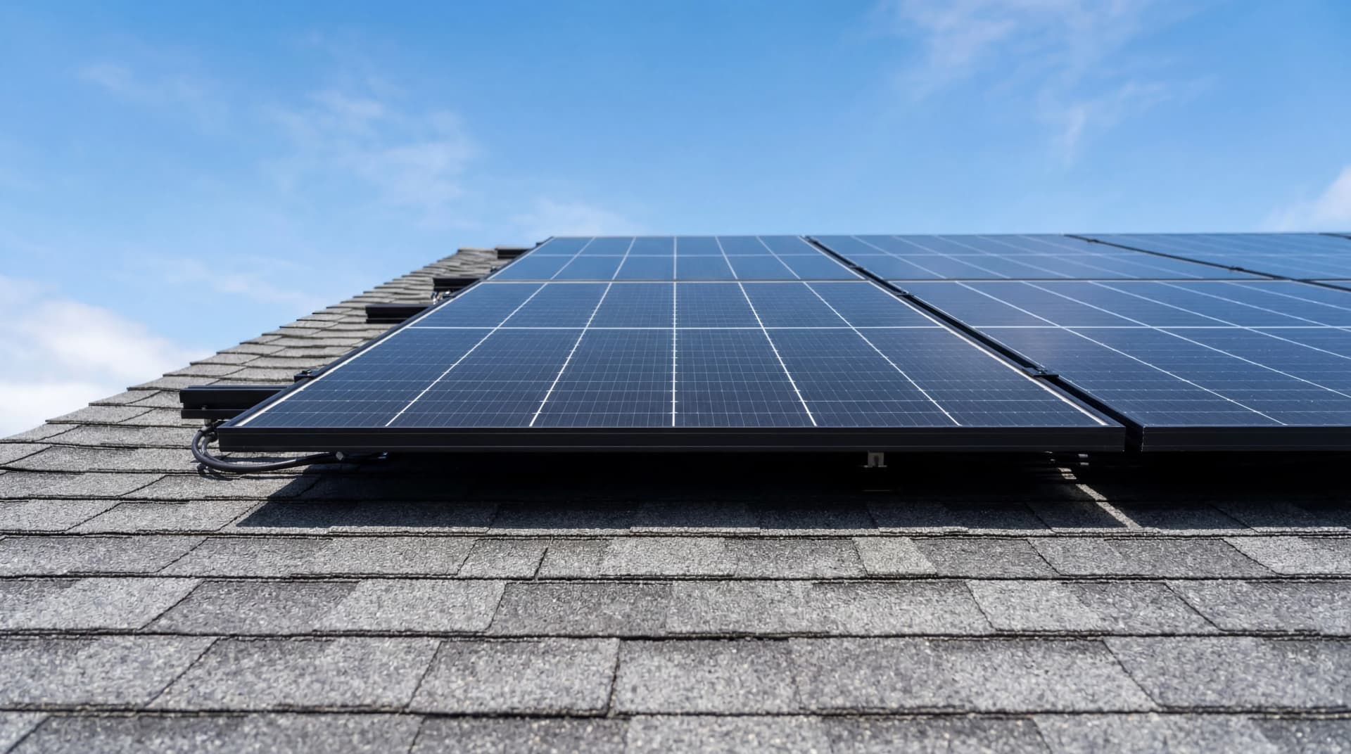 Close view of black solar panels mounted on a residential shingle roof